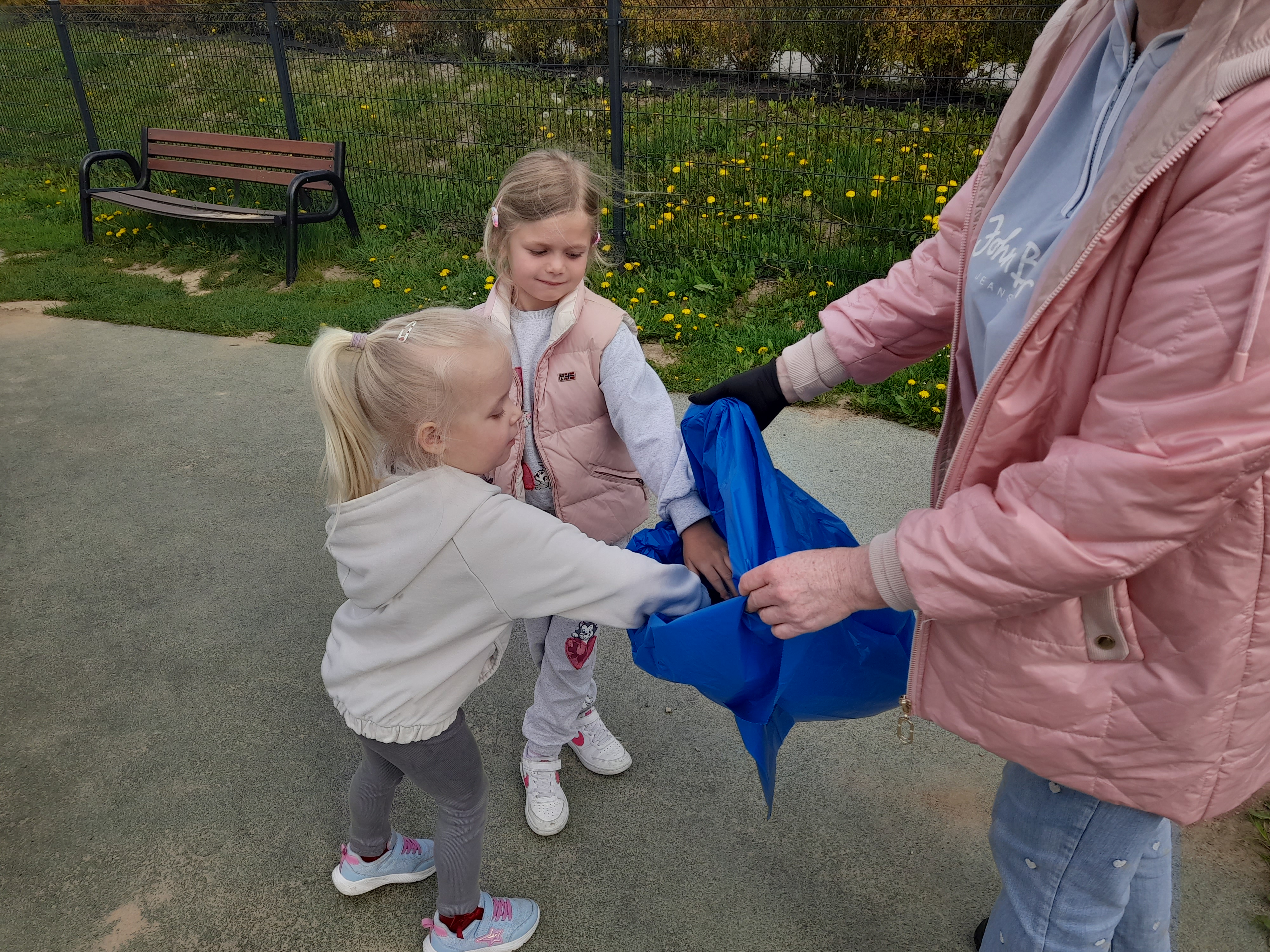 Sprzątanie Świata - Dzieci z przedszkola zbierające śmieci do niebieskiego worka na terenie przedszkola.