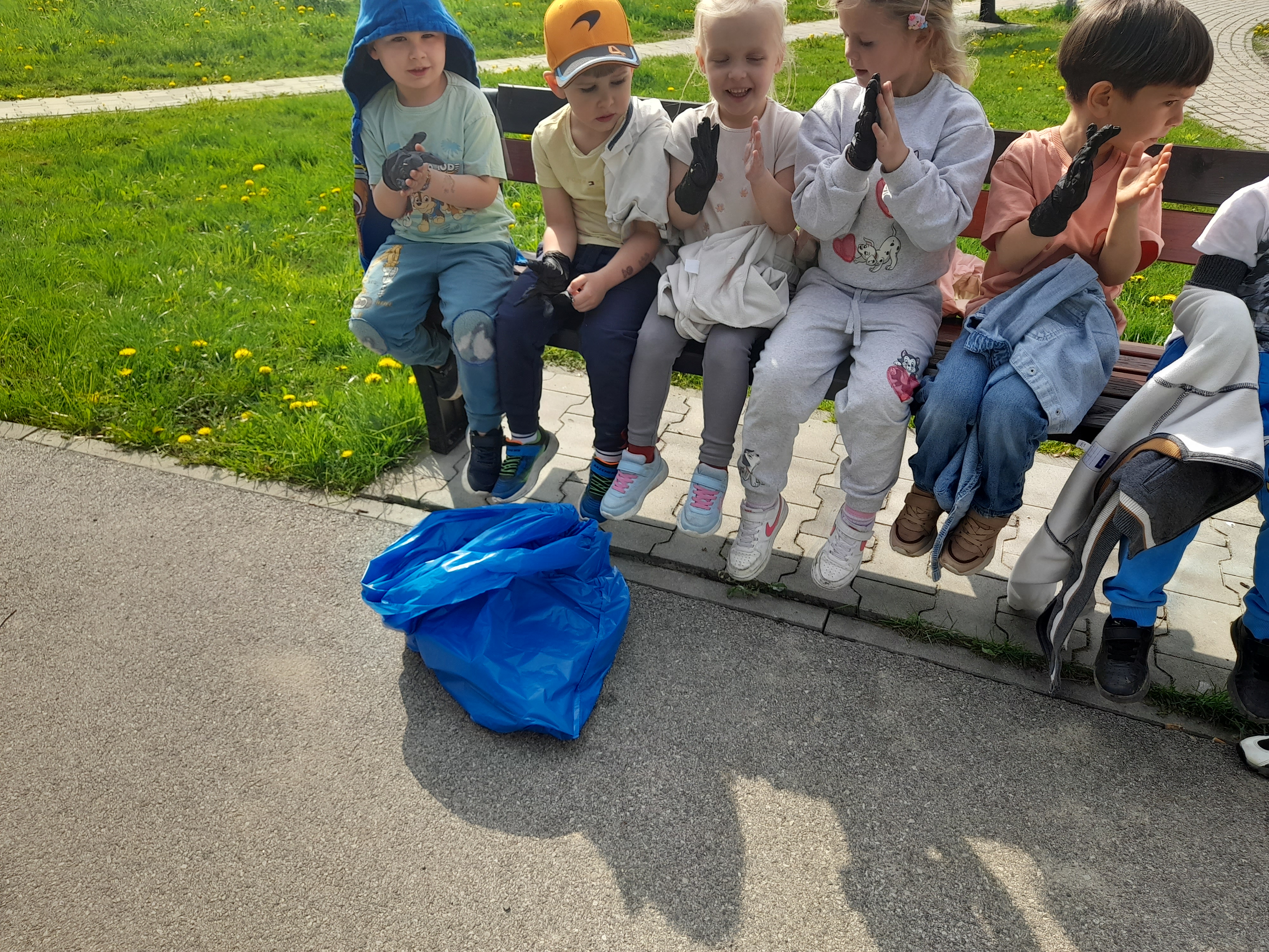 Sprzątanie Świata - Dzieci z przedszkola odpoczywające na ławce po zakończeniu akcji sprzątania, z pełnym workiem śmieci.