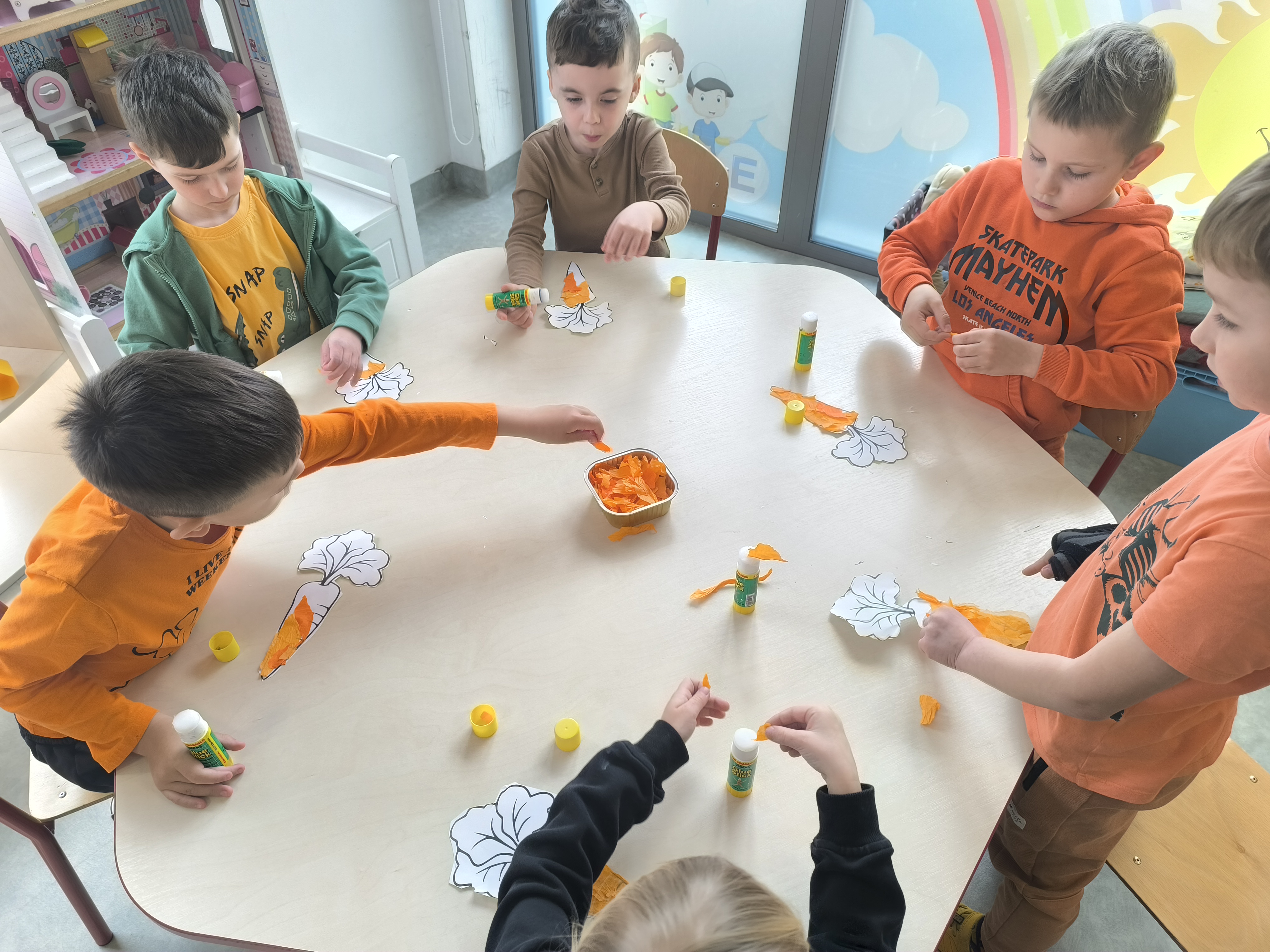 Dzień Marchewki - Dzieci wyklejające marchewki bibułą podczas zajęć w przedszkolu.