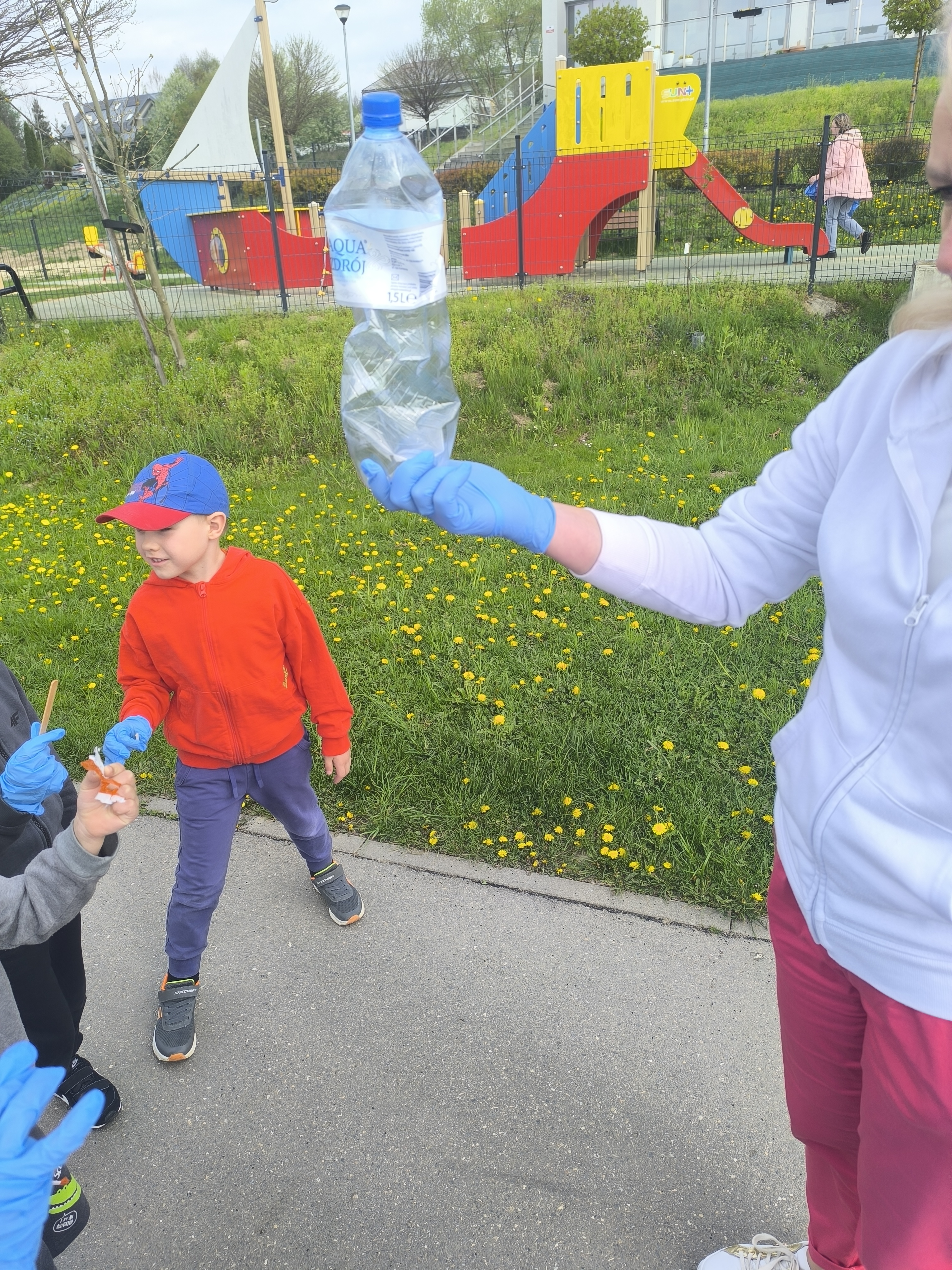 Sprzątanie Świata - Dzieci z przedszkola podczas zbierania plastikowych butelek na placu zabaw.
