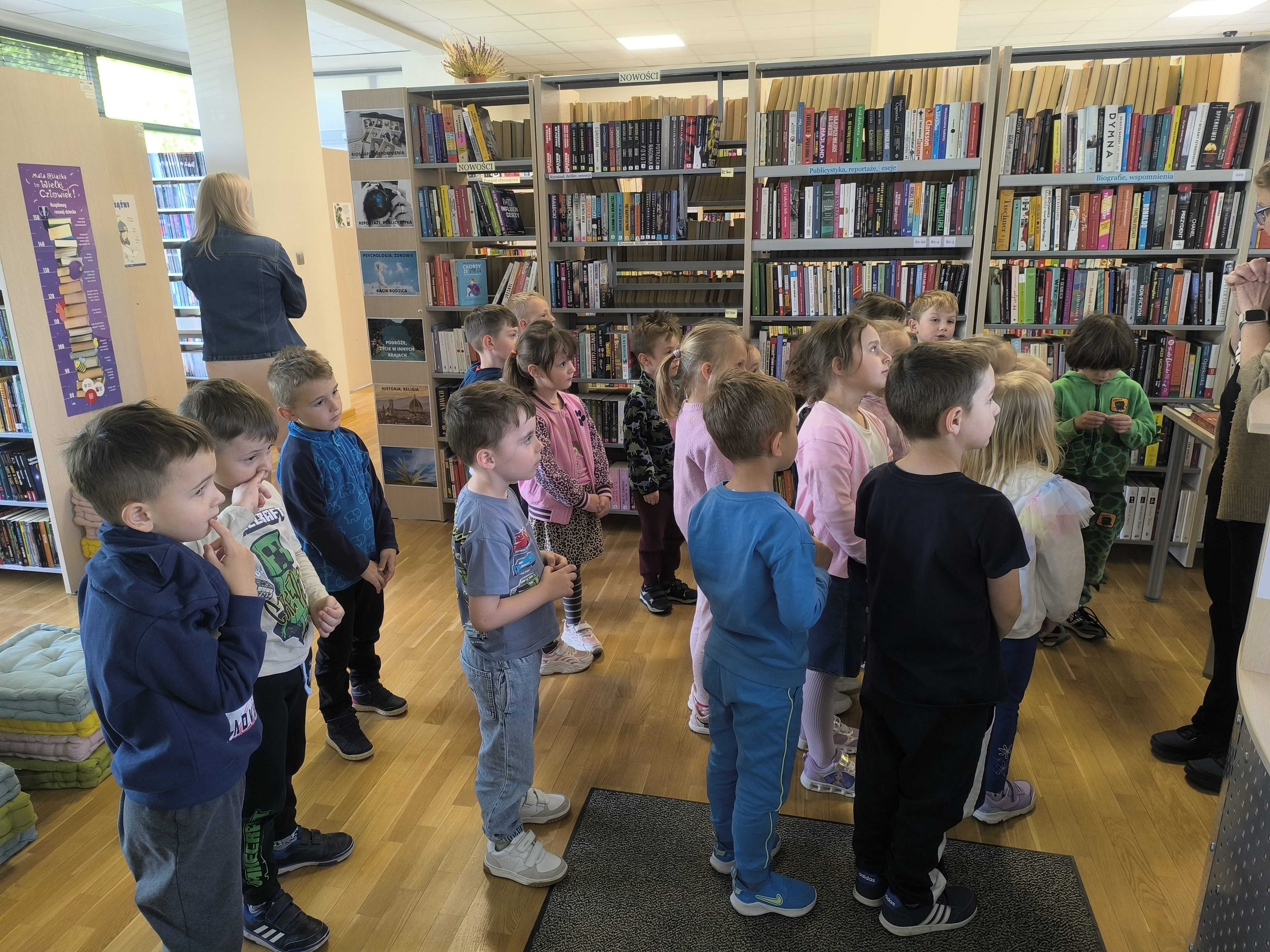 Dzień Biblioteki - Dzieci z przedszkola uważnie słuchające opowieści podczas wizyty w bibliotece.