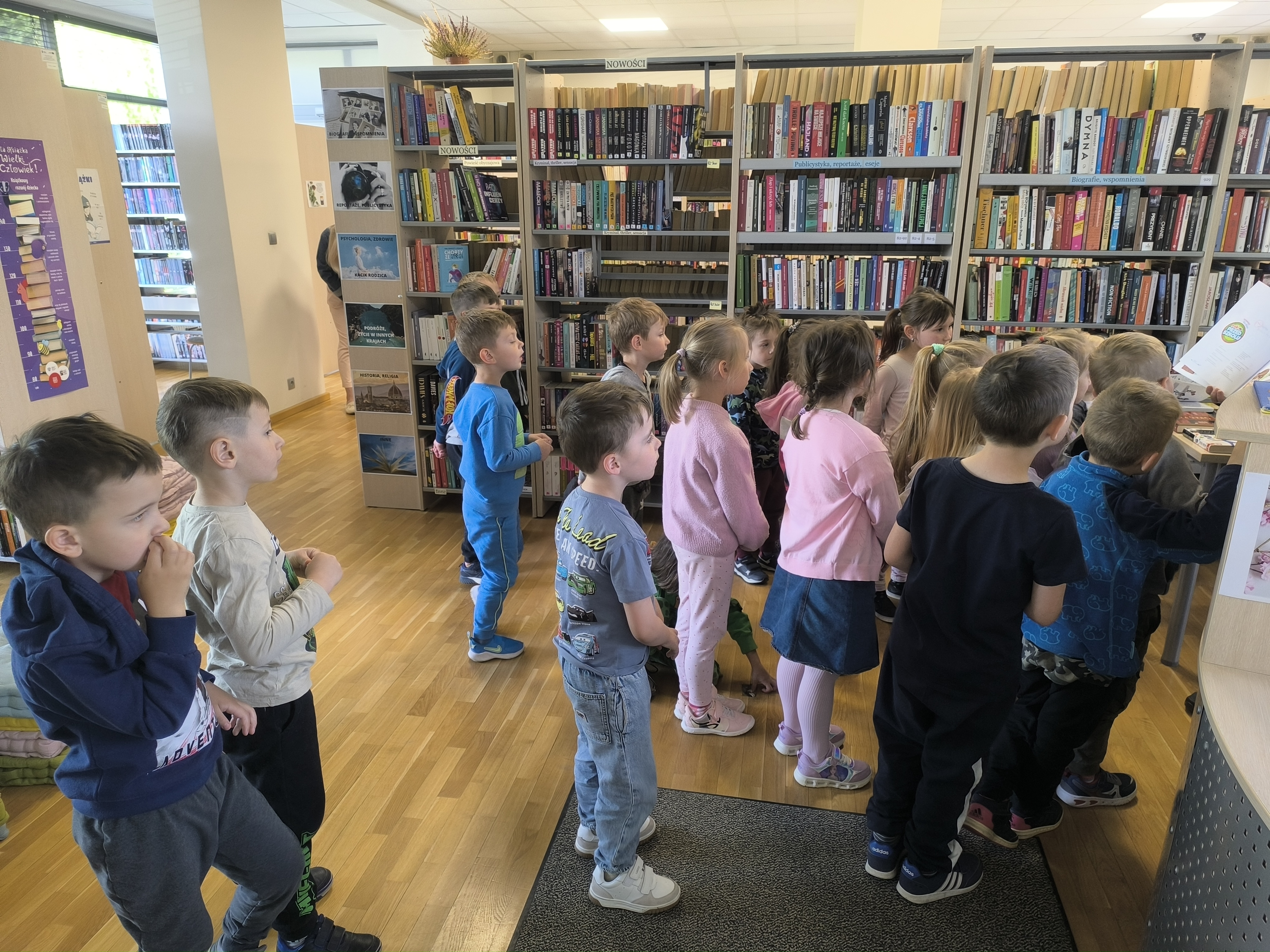 Dzień Biblioteki - Dzieci z przedszkola uważnie słuchające opowieści oraz oglądające kolorowe książki w bibliotece.